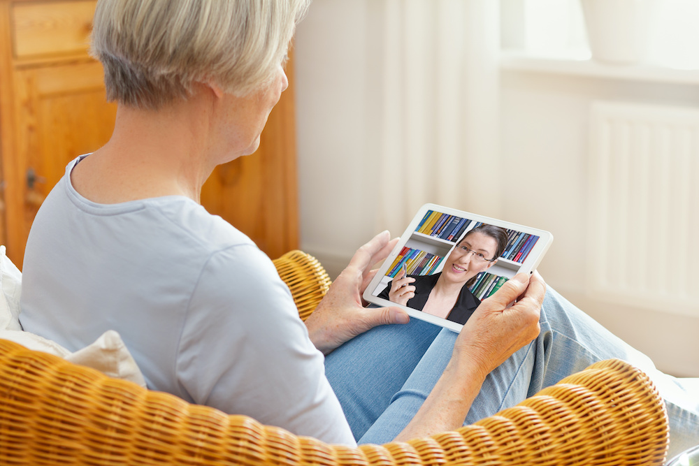 Teletherapy concept, senior woman talking with her counselor or laywer during a live call on her tablet pc at home